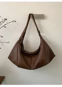 Detailed texture of caramel brown lychee leather on a large pleated hobo bag