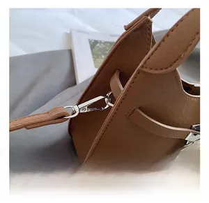 Close-up of brown bucket bag featuring silver metal hooks and premium leather stitching