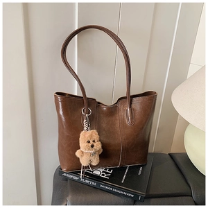 Detail of dark brown wax leather tote bag with a cute plush bear pendant accessory