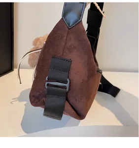 Detail of durable strap connection on brown suede tote bag with black strap and charm