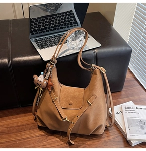Brown faux leather tote bag with cute bear charm shown next to a laptop and books