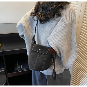 Dettaglio di una borsa a secchiello vintage in pelle scamosciata nera con cuciture bianche