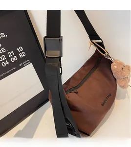 Detail of brown suede tote bag featuring a cute teddy bear charm and adjustable strap