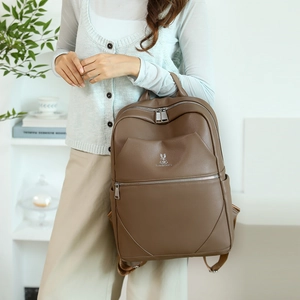 Detail showing high-quality lychee texture leather and silver zipper on the brown backpack