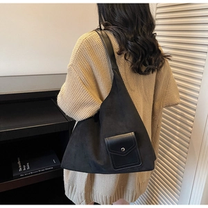 Dettaglio della borsa tote in pelle scamosciata nera con pratica tasca frontale con patta