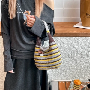 Detail shot of striped knitted bucket bag with a cute brown mushroom pendant accessory
