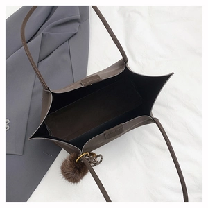 Macro view of large tote bag with magnetic closure, dark brown leather, and pompom charm