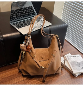 Close-up of caramel faux leather tote bag with stylish charms and metal hardware details