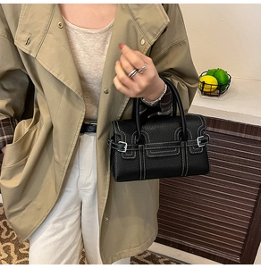 Nahaufnahme der schwarzen Lederhandtasche mit weißen Kontrastnähten und runden Griffen