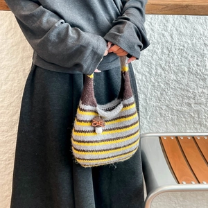 Detail of hand-knitted striped bucket bag featuring a cute mushroom charm and bow