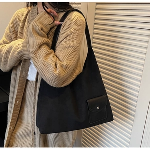 Dettaglio borsa tote in camoscio nero con tracolla in pelle e tasca anteriore a bottone