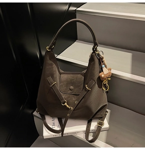 Detail of dark brown suede shoulder bag with gold hardware and plush bear charm