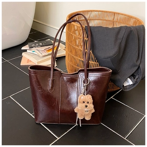 Detail of dark brown wax leather tote bag with a cute plush dog pendant charm