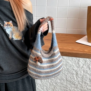 Detail of striped knit bucket bag featuring a 3D mushroom charm and woven texture