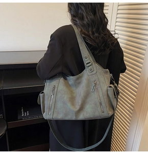 Rear view of grey-green large tote bag with zipper details on black outfit
