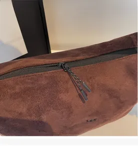 Detail of smooth black zipper with woven puller on large brown suede tote bag