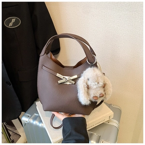 Detail view of coffee leather bucket bag with gold magnetic buckle and plush bunny charm