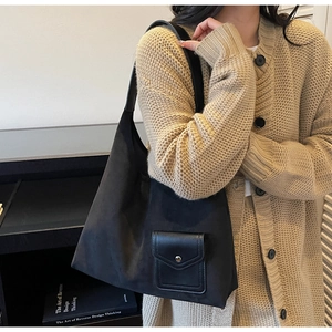 Dettaglio della borsa tote nera con tasca frontale impunturata e tracolla in pelle nera