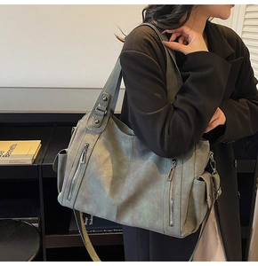 Olive green tote bag with vertical zipper pockets and adjustable shoulder strap shown in use