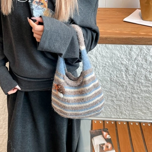 Detail of hand-knitted striped bucket bag with a cute mushroom charm accessory