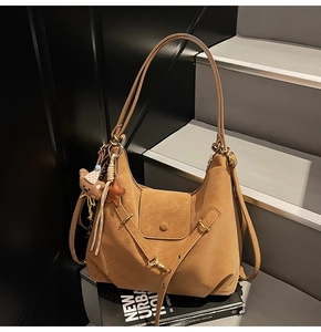 Detail of tan suede hobo bag featuring bear charm, star pendant, and gold metal hardware