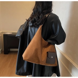 Detail of brown suede hobo bag with dark leather pocket and metallic snap button