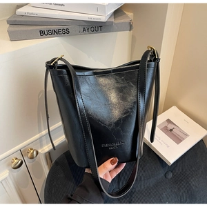 Detail of black washed leather bucket bag with retro gold hardware and embossed text