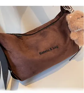 Detailed view of dark brown suede bag with Banatu embroidery and plush bear charm