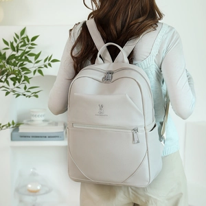 Close-up of beige lychee leather backpack with silver rabbit logo and metal hardware