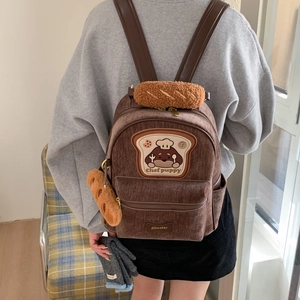 Detail of brown corduroy backpack with cute chef puppy toast patch and baguette charm