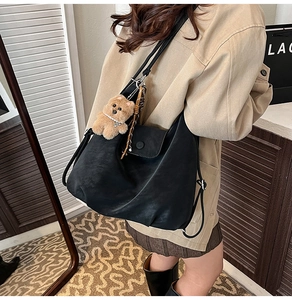 Vue latérale du grand sac hobo en similicuir noir avec un charmant ours en peluche