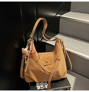 Detail of vintage brown tote bag with plush bear charm and star pendant on textured leather
