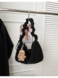 Detail of black matte tote bag with pleated handle and cute brown plush bear charm