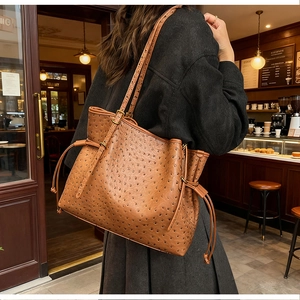 Detail of dark brown ostrich texture leather on large tote bag with side drawstring