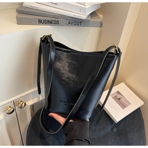Detail of black oil-wax leather bucket bag showing the fashion logo and gold hardware