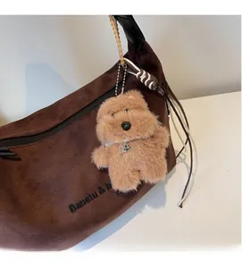 Detail of plush dog charm with pearl necklace on dark brown suede tote bag