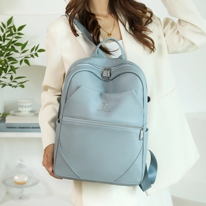 Detail of light blue pebble leather backpack featuring front zipper and rabbit motif