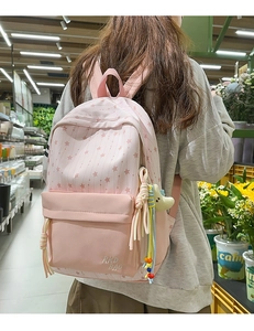 Sac à dos scolaire en nylon rose avec motifs d'étoiles et pendentifs porté par un modèle