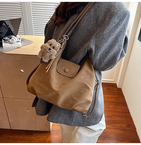 Détail d'un sac cabas vintage marron foncé avec un joli pendentif chiot en peluche