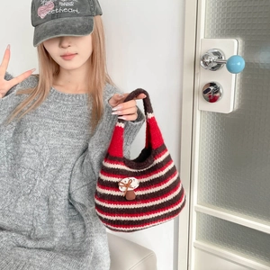 Detail of hand-knitted striped bucket bag featuring mushroom decor and red stripe pattern