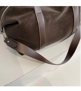Detail of dark brown leather travel bag featuring white contrast stitching and silver hardware
