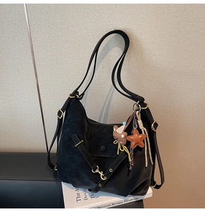 Close-up of black retro tote bag with brown bear charm and gold metal hardware detail