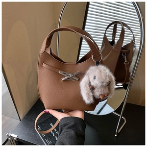 Close-up of brown litchi pattern bucket bag with silver bow lock and plush bunny charm