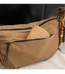 Detail of caramel nylon hobo bag showing fabric texture, wooden beads and small pouch