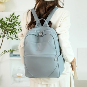 Detailed view of light blue leather backpack with rabbit logo worn by model in home setting