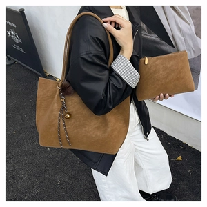 Close-up of brown matte tote bag and matching pouch worn by model in street scene