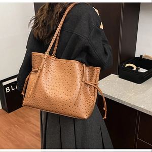 Detail of brown ostrich leather embossed tote bag with slim straps and side drawstrings