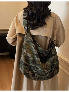 Large camouflage canvas tote bag worn by model with an adjustable shoulder strap