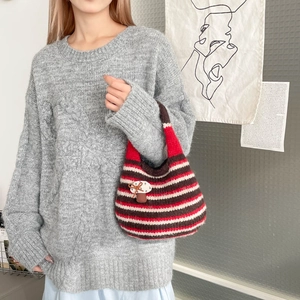 Detail of striped knit tote bag featuring a cute mushroom charm and bow accent