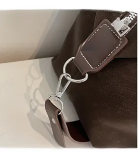 Detail of dark brown leather tote bag showing silver metal hooks and fine stitching